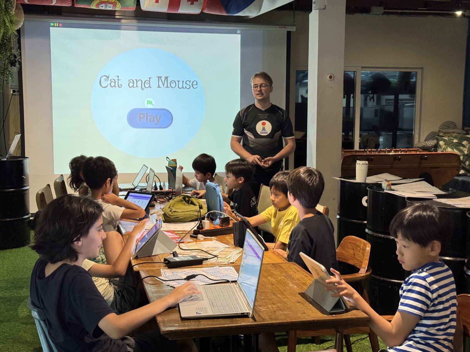 Kids coding on laptops with a Scratch game on the projector screen